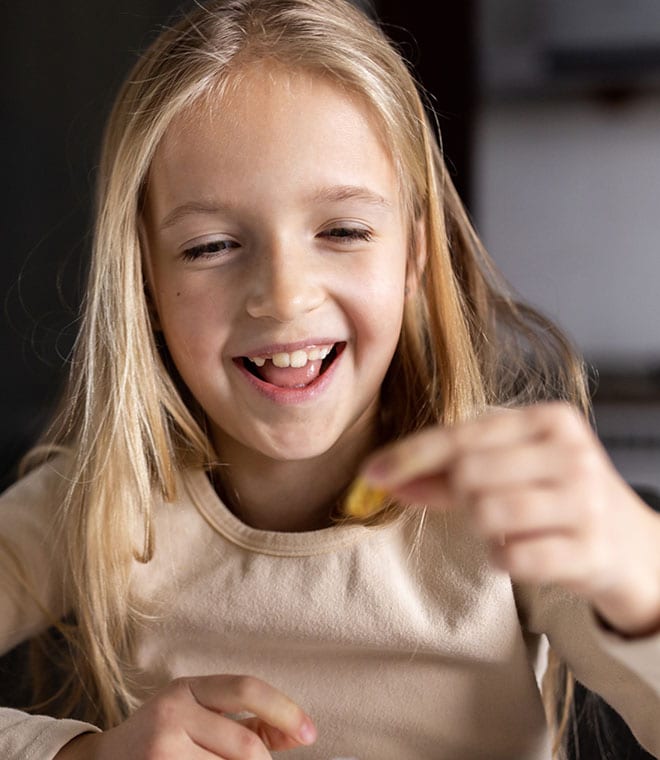 Little blonde girl smiling and eating food