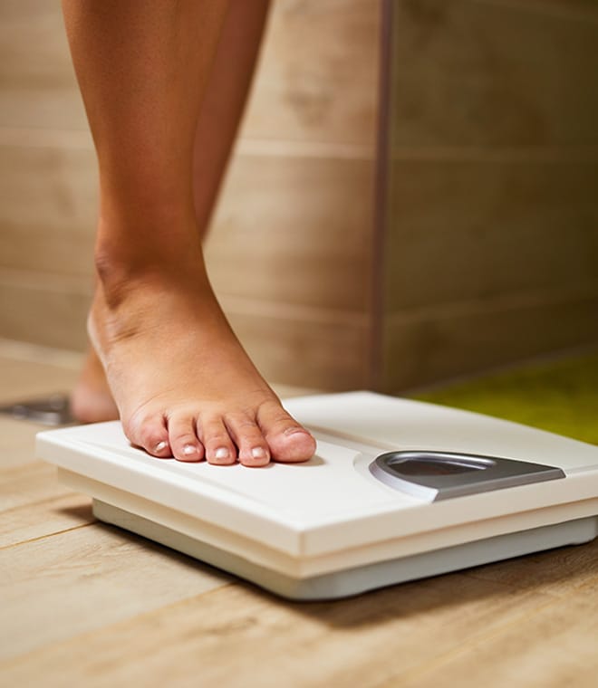 Woman stepping on white scale