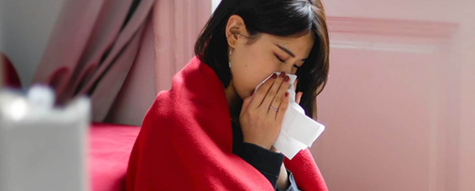 woman sneezing into a kleenex