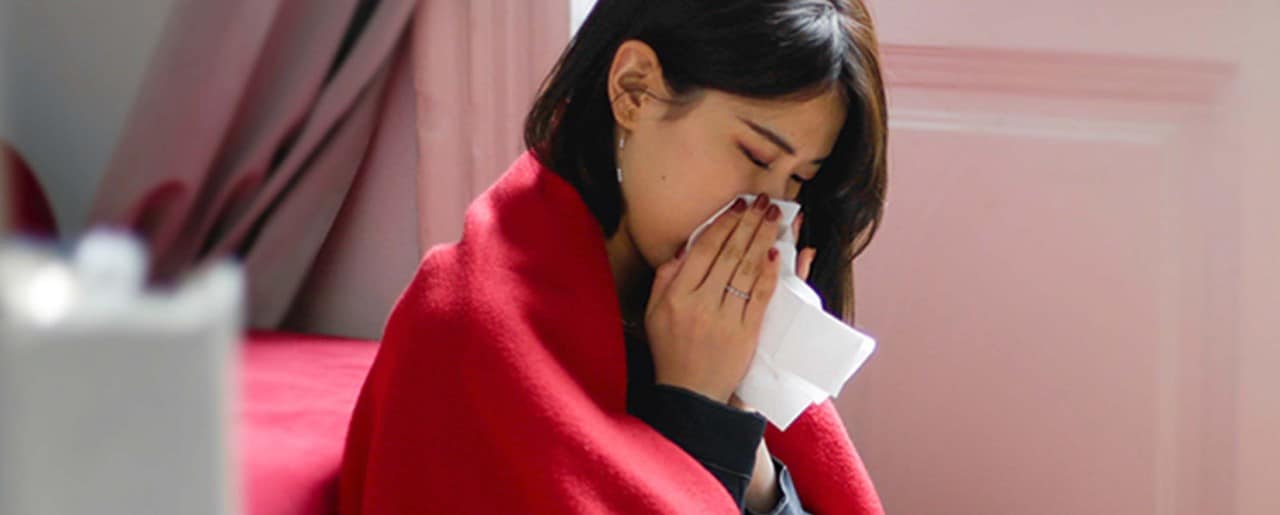 Young Asian woman blowing her nose