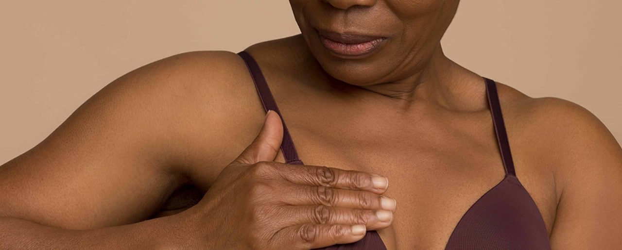 Middle aged black woman checking her breast for lumps