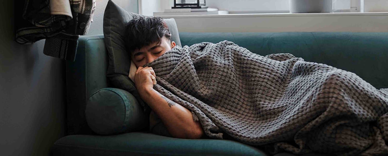 man sleeping on a couch sick with a cold