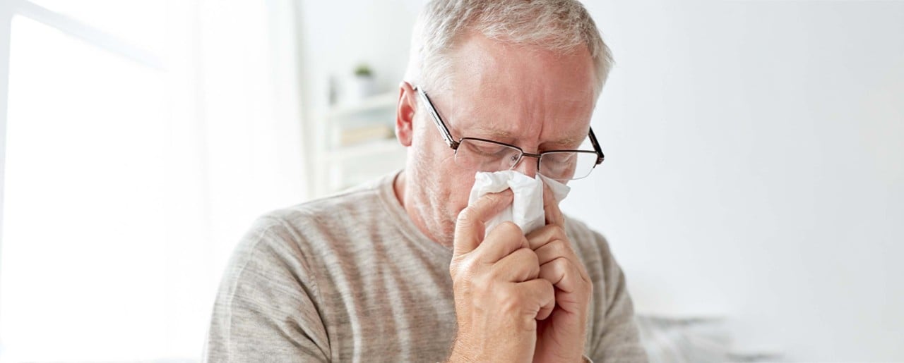 old man blowing nose with a wipe