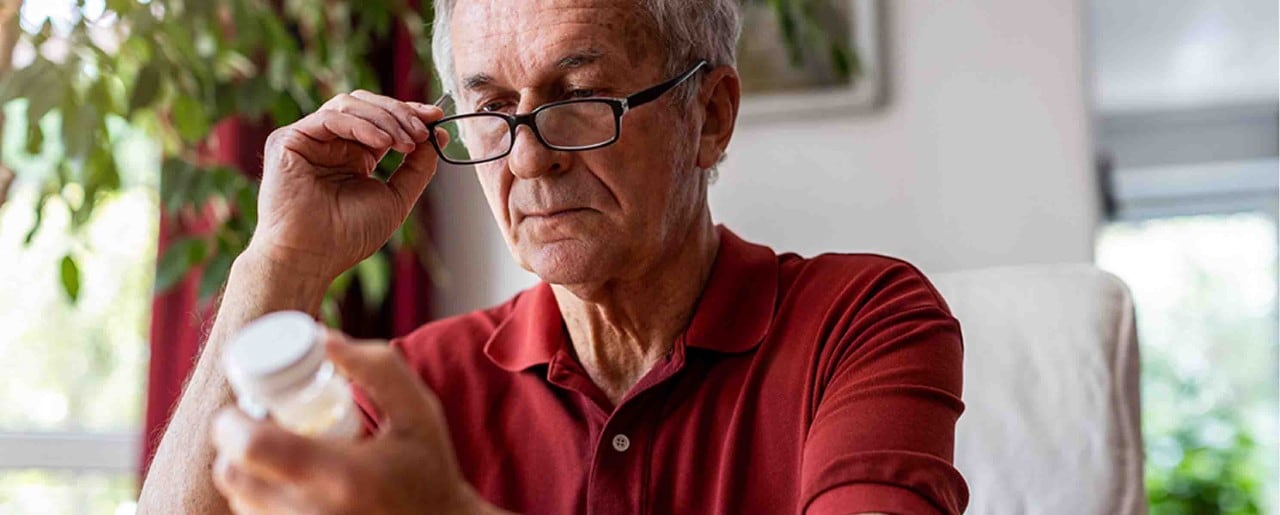 Older white man reading pill bottle