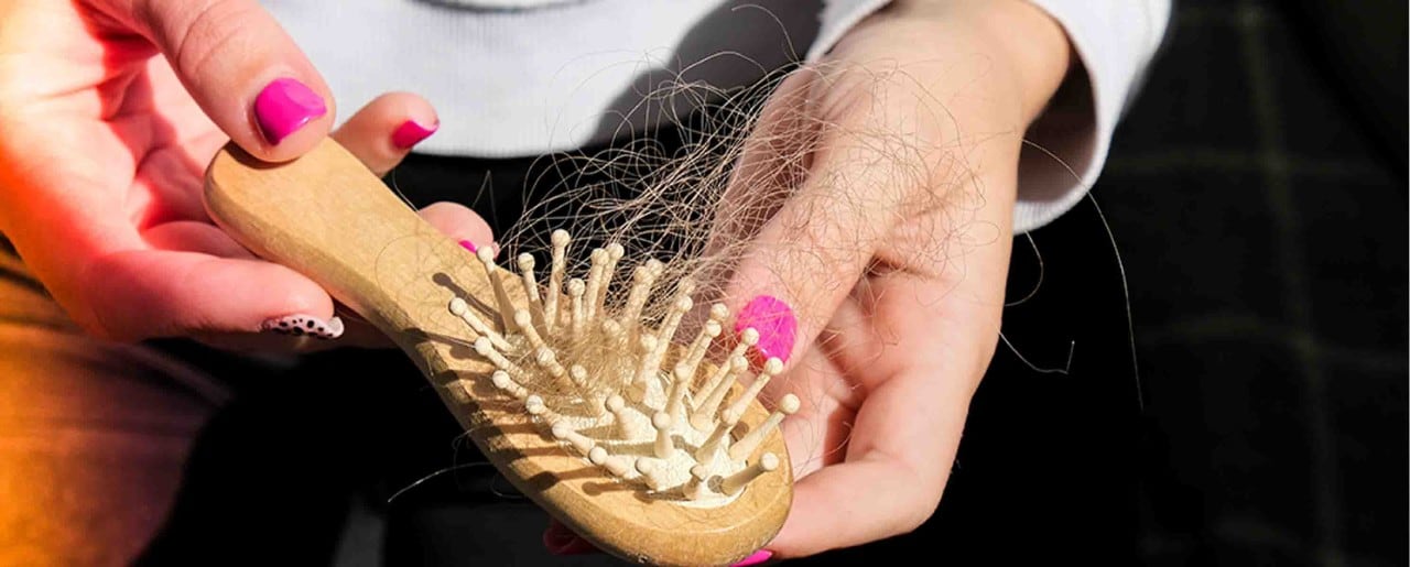 White woman pulling hair out of a brush