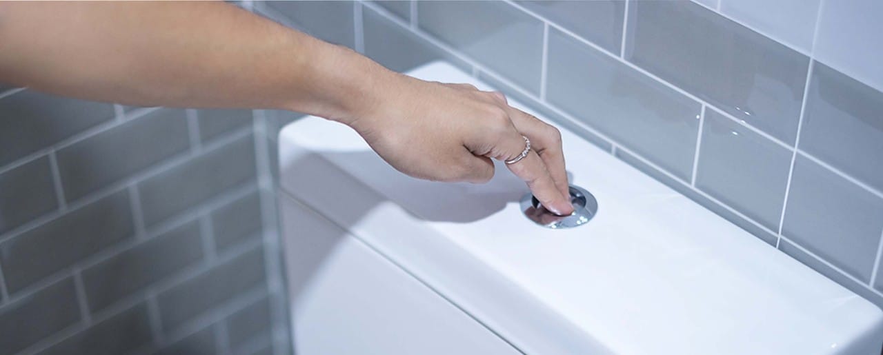 White woman's hand flushing a toilet