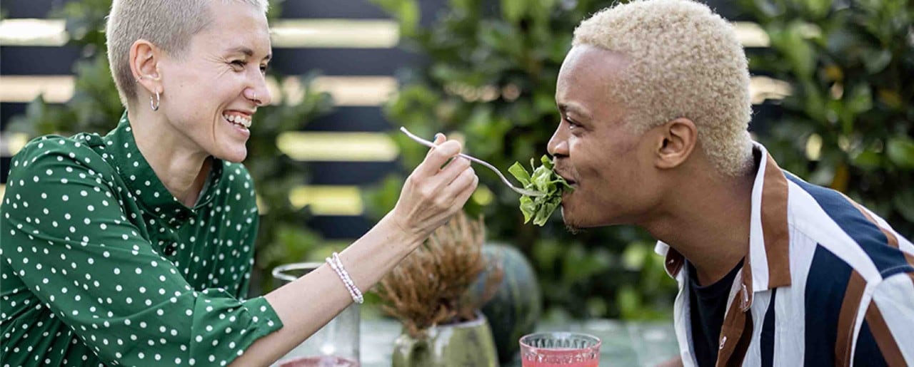 Interracial couple in their 30s sharing a salad